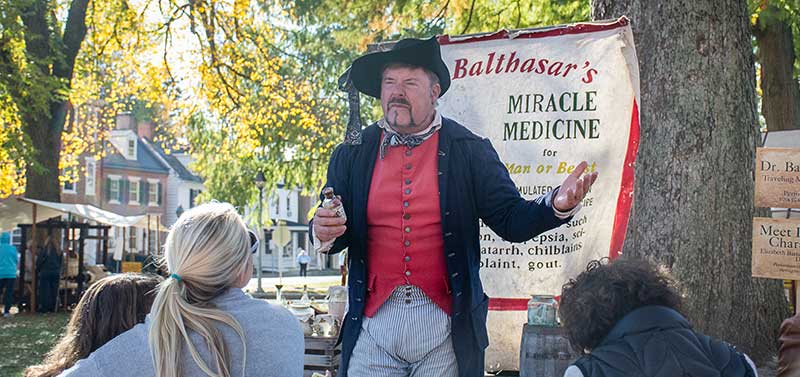 man dressed in 1700s clothes enacting medicine sales